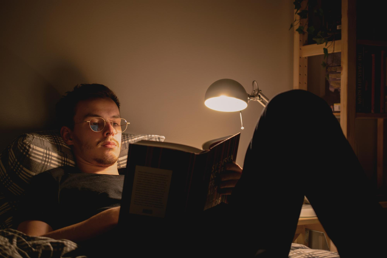Person reading in a softly lit corner during evening relaxation